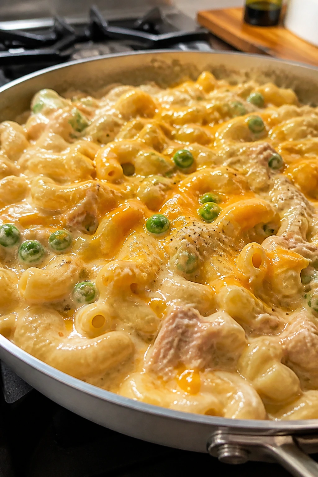 Creamy tuna pasta with cheddar and peas in a skillet