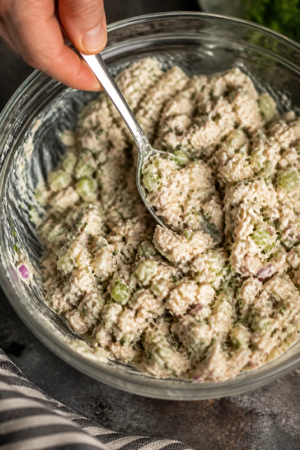 Hands mixing tuna salad in a bowl