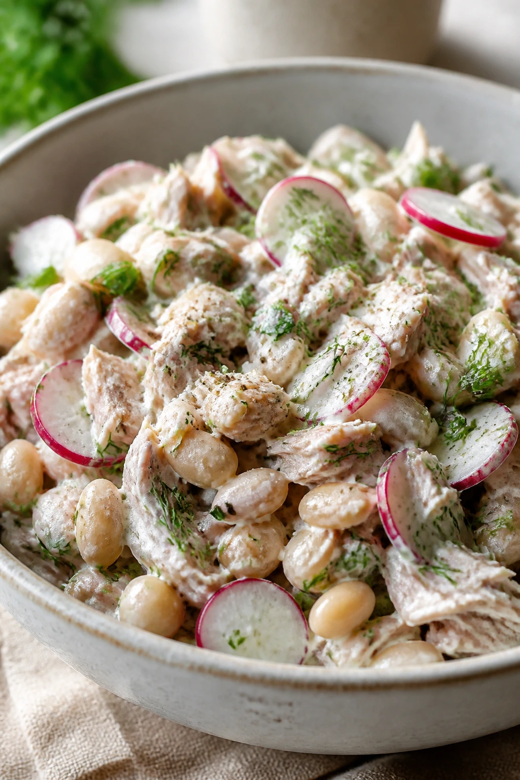 Close-up of Yogurt-Dressed Tuna Salad with Radish and Herbs featuring tuna, white beans, yogurt, radish, and herbs.