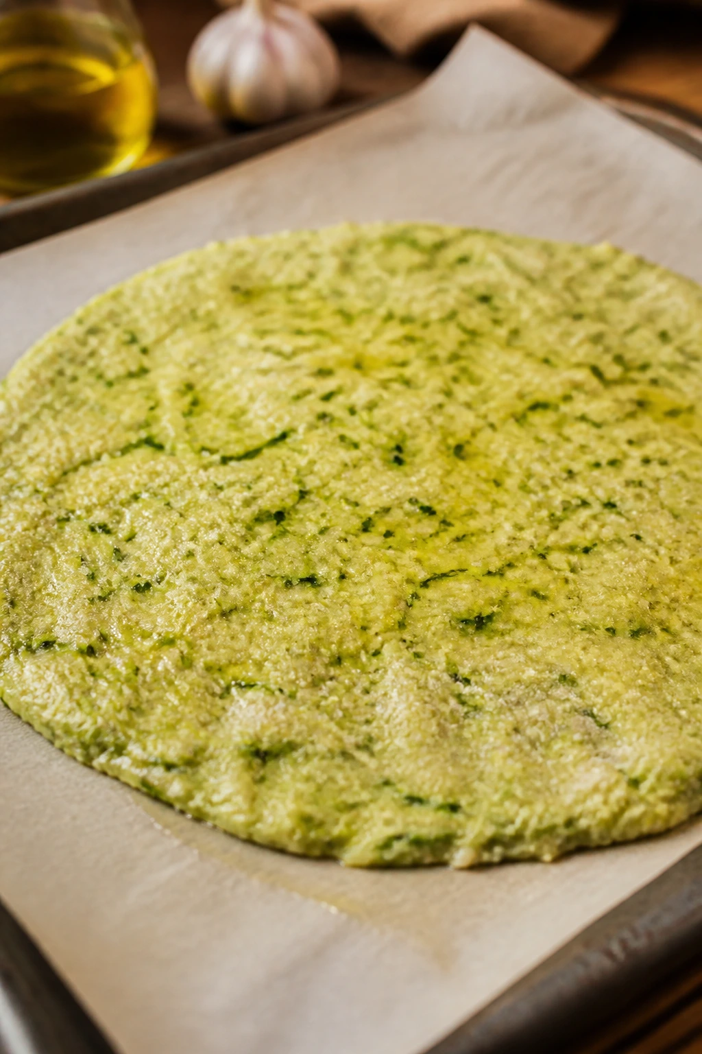 Raw zucchini dough disk on parchment on a pan